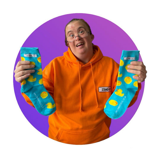 A Lady who has Down Syndrome holding up a pair of blue socks with rubber ducks socks 