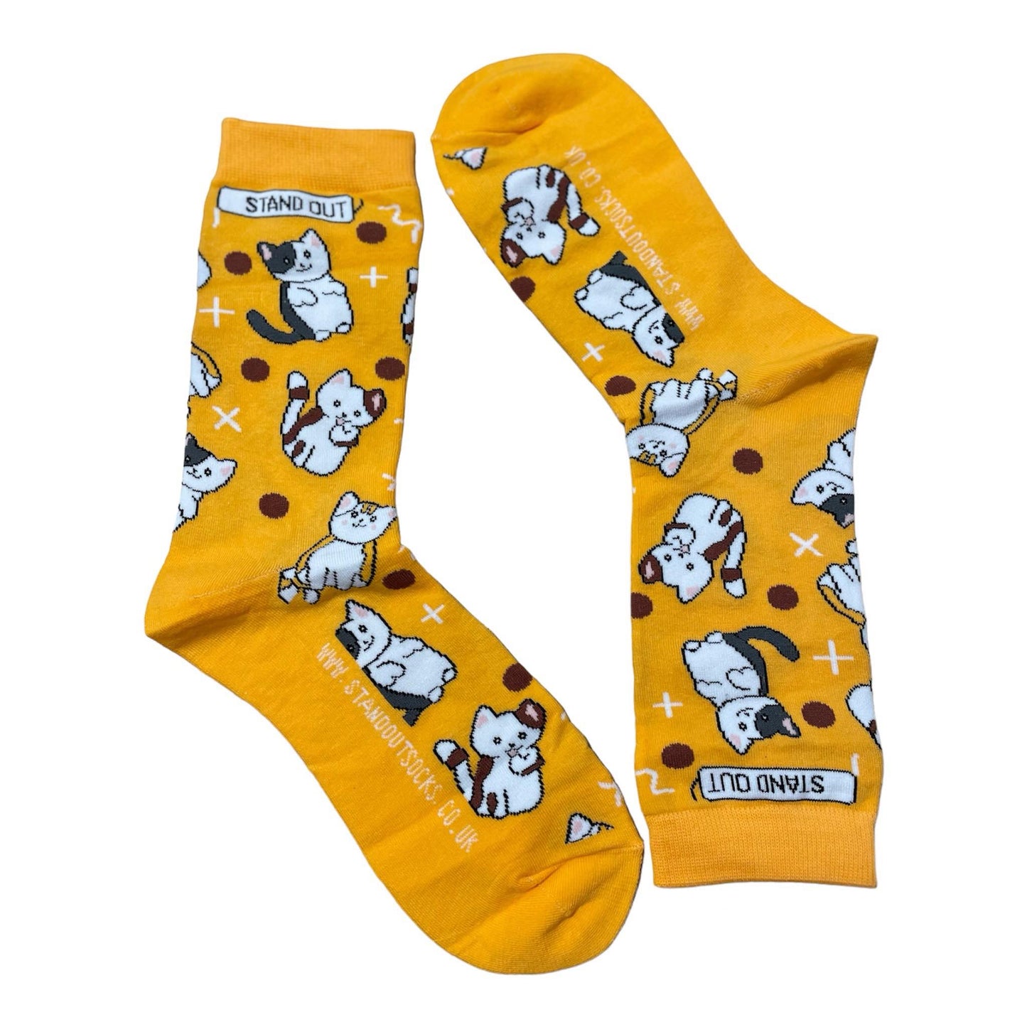 Orange socks featuring a cute cat pattern, created by Stand Out Socks. The socks display a playful design with brown and white cats and shapes scattered throughout. The words "STAND OUT" are visible on the cuff and the company's website is printed on the sole.