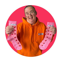 Load image into Gallery viewer, Lady with orange jumper on holding up a pair of pink socks with tomato pattern, surrounded by a pink circle border.
